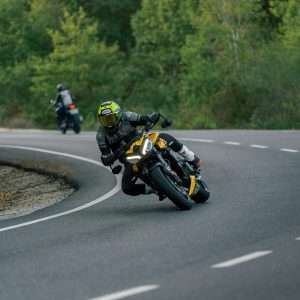 Thrilling motorcycle racing on a scenic curved country road surrounded by lush greenery.