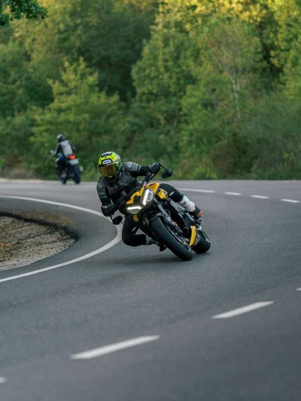 Thrilling motorcycle racing on a scenic curved country road surrounded by lush greenery.