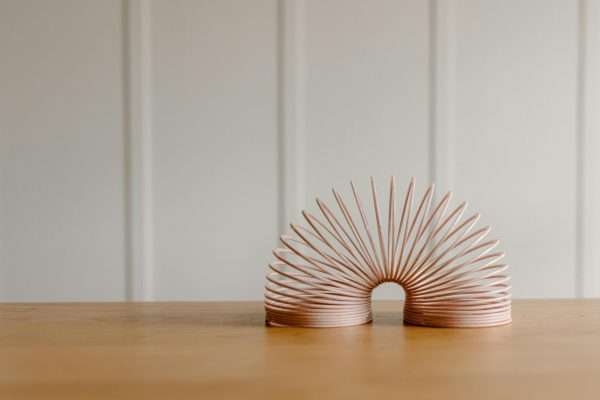 A minimalist photo of a pink slinky toy on a wooden surface indoors, offering a playful and modern aesthetic.