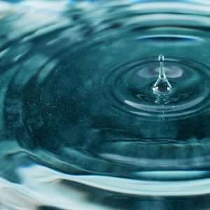 A mesmerizing close-up image of a water droplet creating ripples on the surface.